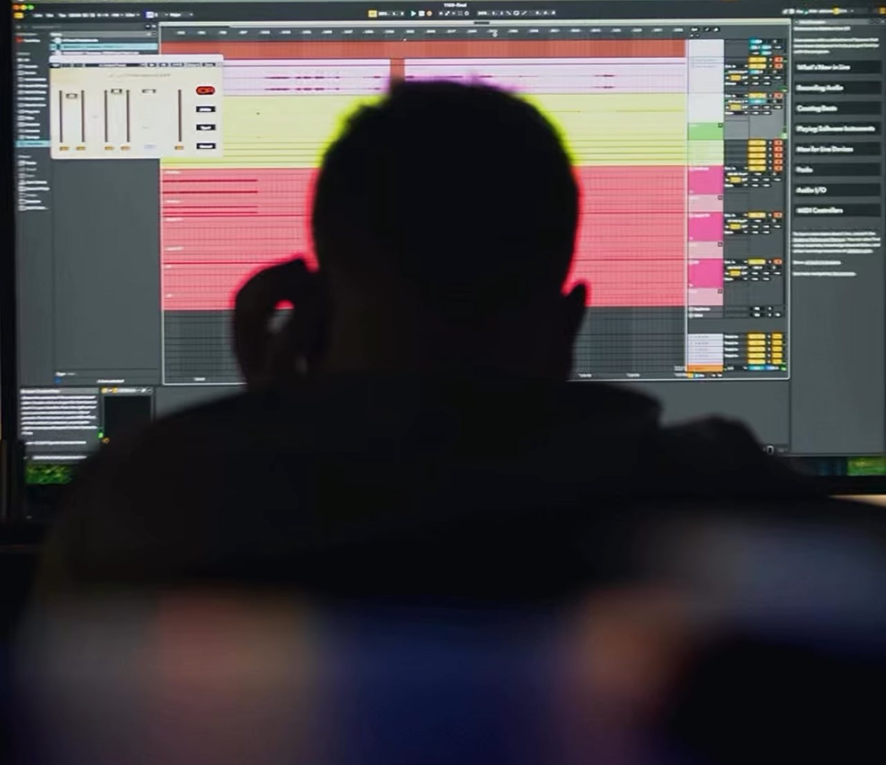 A producer seen from behind in front of a studio screen with the arrangement